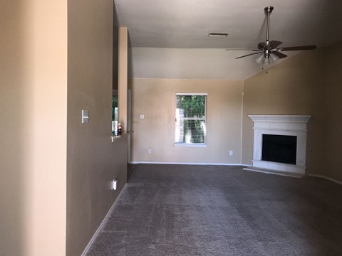 a living room with a fireplace and a ceiling fan